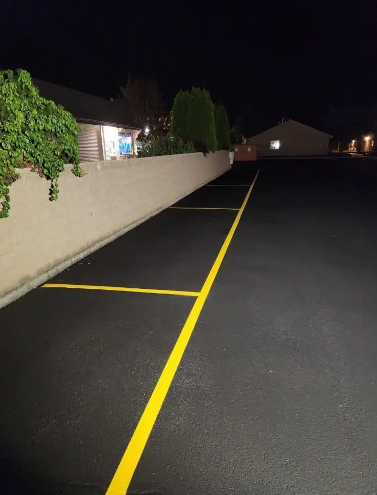 A freshly painted yellow stall line along a block wall at night