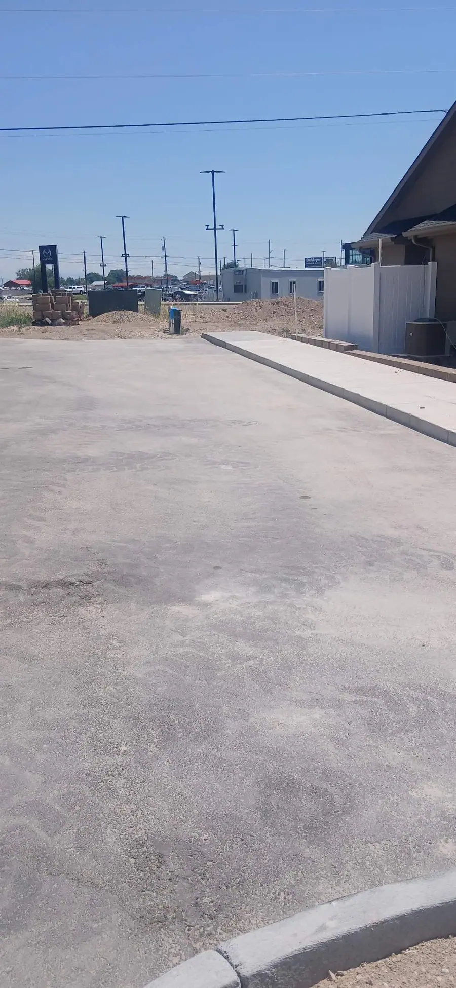 A swept lot and fresh curbing next to a new commercial building